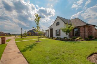 white and brown house near green grass field under white clouds and blue sky during daytime by Ronnie George courtesy of Unsplash.