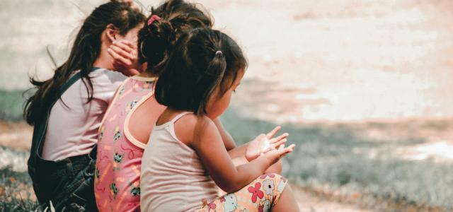 three children sitting on grass by Charlein Gracia courtesy of Unsplash.