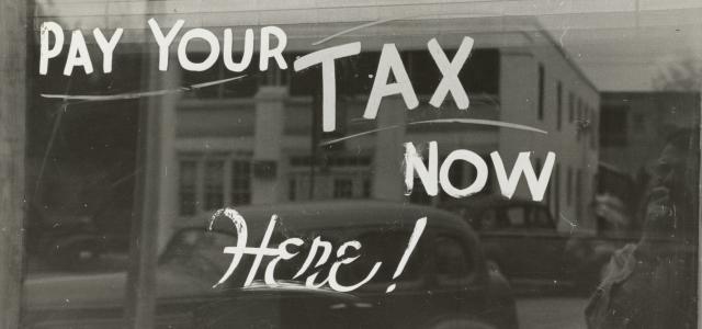 a sign that says pay your tax now here by The New York Public Library courtesy of Unsplash.
